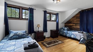 Une chambre avec deux lits, une commode, une lampe et une fenêtre avec des rideaux.
