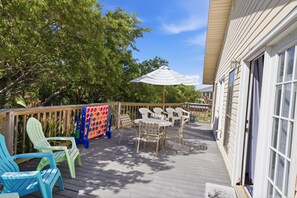 A wooden deck with outdoor furniture, a colorful board game, and a large umbrella. - Island Palms- Pet Freindly- 3 Bedroom SGI (Saint George Island)