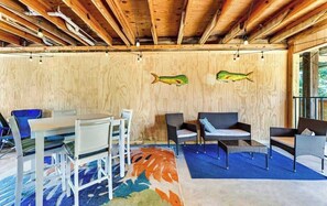 A room with a wooden ceiling, a dining table with chairs, a blue rug, and two fish wall art pieces. - Island Palms- Pet Freindly- 3 Bedroom SGI (Saint George Island)