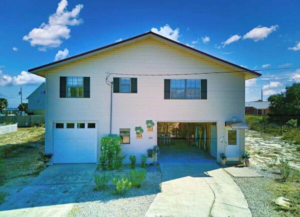 A two-story house with a garage, a small porch, and a driveway. - Island Palms- Pet Freindly- 3 Bedroom SGI (Saint George Island)