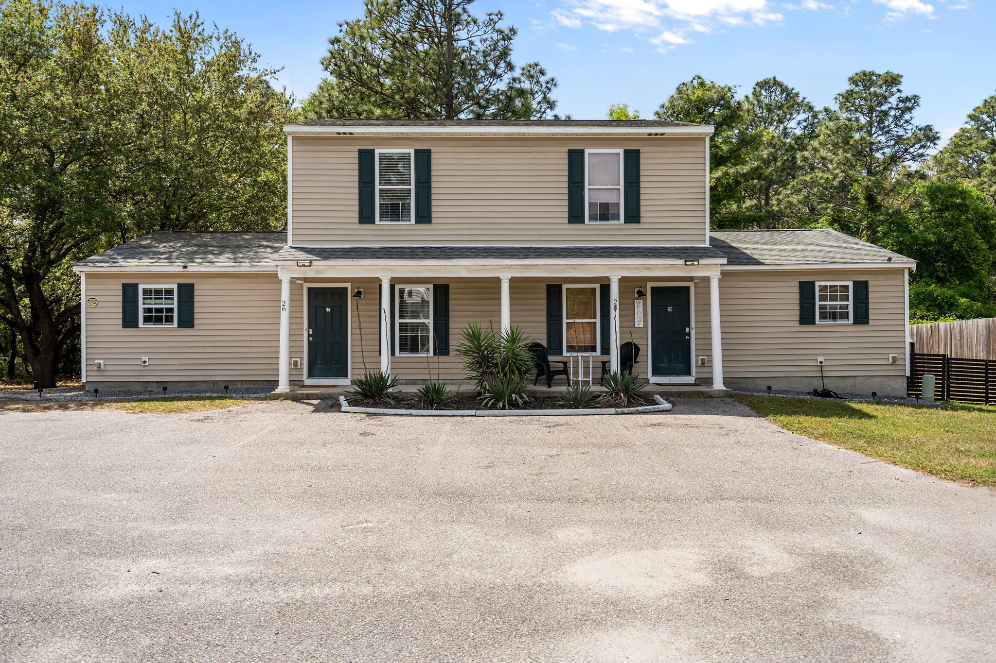 A two-story house with a front porch, a driveway, and a fenced yard.