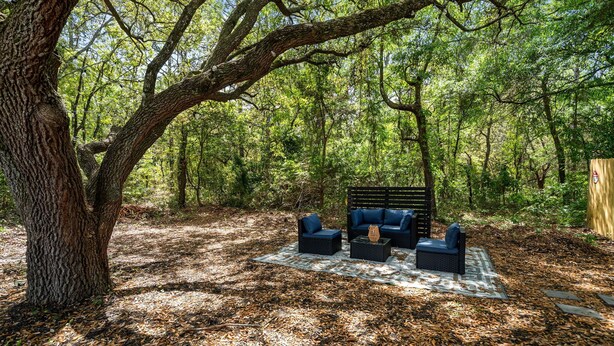 A forested area with a seating arrangement under a large tree. - Portside Retreat: Quiet wooded stay, where everything just short drive away (Wilmington)
