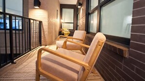 Ein Balkon mit zwei Holzstühlen, einem kleinen Tisch und einem Geländer.