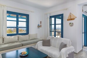 Ein Zimmer mit einer Couch, einem Tisch mit einer Schale und zwei Fenstern mit blauen Rahmen.