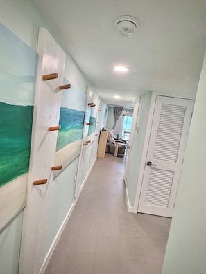 A hallway with a painted wall, a ceiling light, and a door with louvered panels. - Quiet north side condo. Beach access, inspiring views, pool. (Fort Myers Beach)