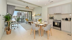 A modern apartment with a dining area, kitchen, and a balcony with a view. - Work & Chill 1BR w/ Office + PS5 Dubai Creek (Dubai)