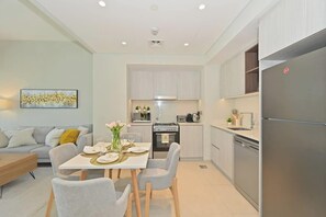 Eine moderne Küche mit eingebautem Ofen, einem Kühlschrank und einem Essbereich mit Tisch für zwei Personen.