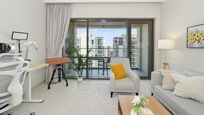 A modern apartment with a balcony, a desk, a sofa, and a coffee table. - Work & Chill 1BR w/ Office + PS5 Dubai Creek (Dubai)