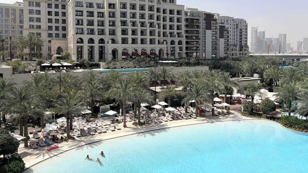 A hotel with a pool area, palm trees, and a view of the city skyline. - Work & Chill 1BR w/ Office + PS5 Dubai Creek (Dubai)
