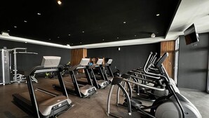 Een fitnessruimte met loopbanden, elliptische trainers en een krachttrainingapparaat.