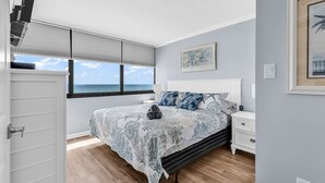 A bedroom with a bed, a nightstand, a window with a view, and a door. - Shore Drive 2 bedroom sleeps 4 Myrtle Beach (Myrtle Beach)