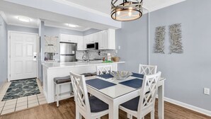 A modern kitchen with white cabinetry, a stainless steel refrigerator, and a microwave. - Shore Drive 2 bedroom sleeps 4 Myrtle Beach (Myrtle Beach)