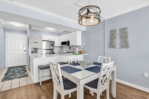A modern kitchen with white cabinetry, a stainless steel refrigerator, and a microwave. - Shore Drive 2 bedroom sleeps 4 Myrtle Beach (Myrtle Beach)