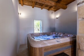 A hot tub in a room with a wooden ceiling and a window. - Mas l'Estelan - Proche Avignon (Saint-Étienne-du-Grès)