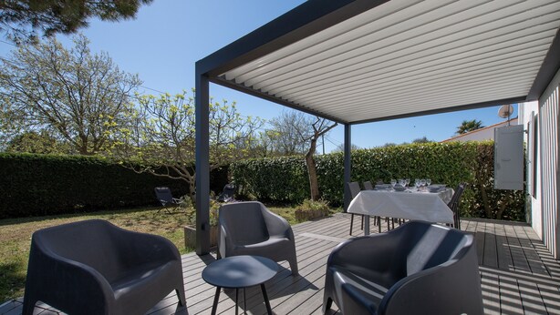 A covered outdoor patio with a table set for dining, surrounded by chairs. - La Maison Orion - Oléron, à 1km de la plage (Dolus-d'Oléron)