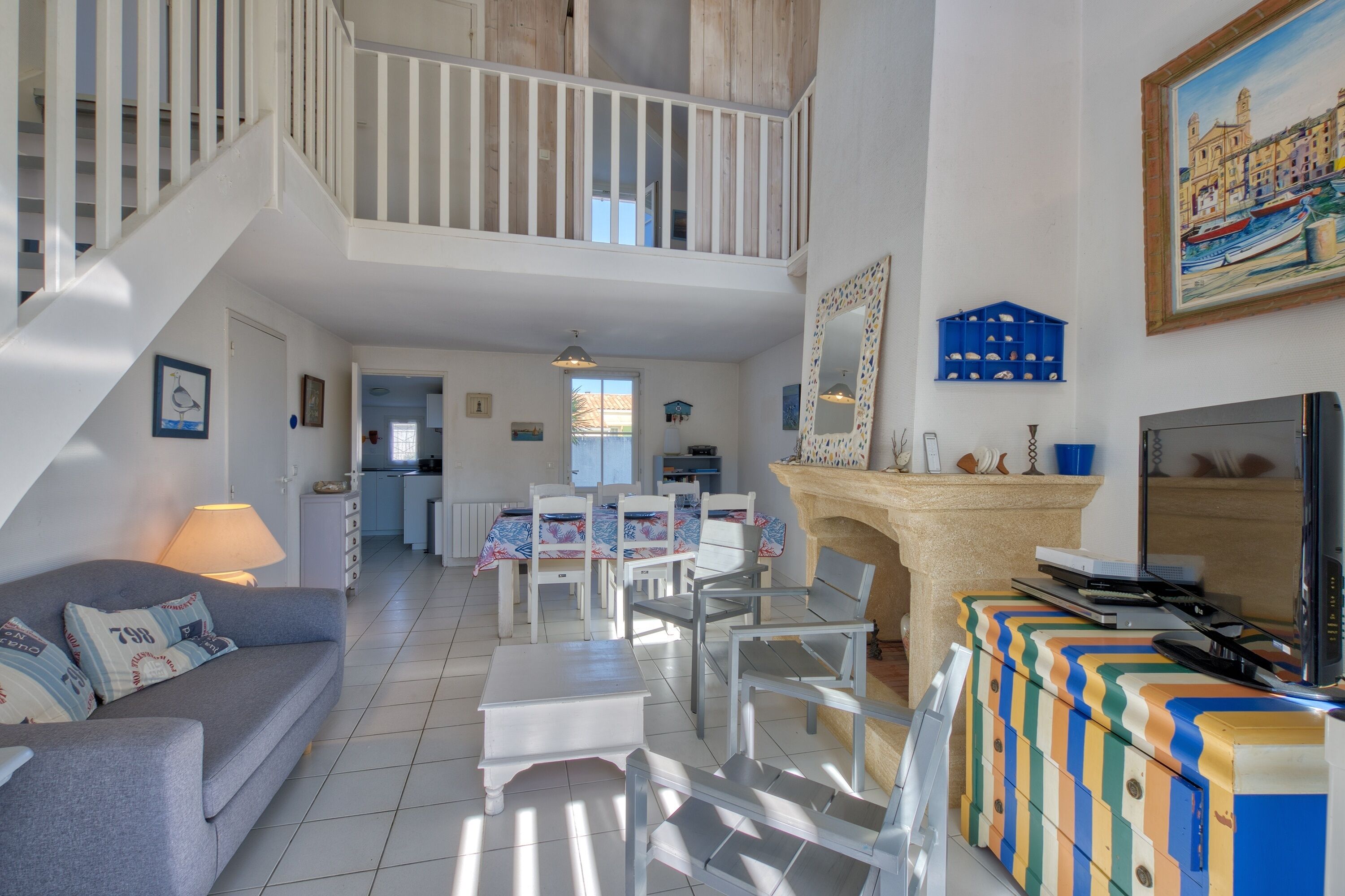 A spacious living area with a staircase, a dining table, and a television.