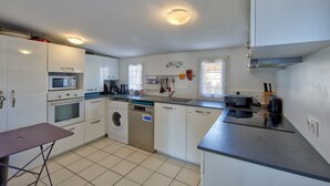 A compact kitchen with a microwave, oven, dishwasher, and a small table. - La Maison Orion - Oléron, à 1km de la plage (Dolus-d'Oléron)