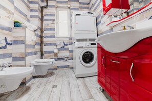 Un baño con lavadora, inodoro, bidé y lavamanos.