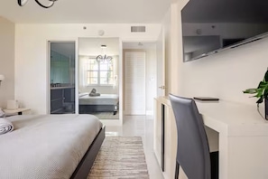 A bedroom with a bed, a desk, a TV, and a door leading to a bathroom. - Cozy 1-bedroom apartment in amazing Miami with AC (Miami)
