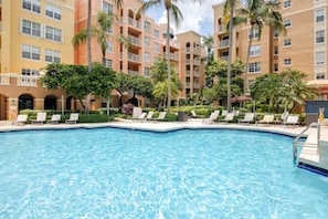 A swimming pool with lounge chairs and palm trees, surrounded by multi-story buildings. - Cozy 1-bedroom apartment in amazing Miami with AC (Miami)