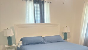 Une chambre à coucher avec un lit, des tables de chevet et une fenêtre avec des rideaux.