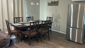 A dining area with a table and chairs, a chandelier, a refrigerator, and a painting on the wall. - New 3-bedroom house in beautiful Douglas with cool AC and warm heat (Douglas)