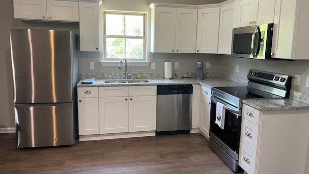 A kitchen with white cabinets, stainless steel appliances, a window, and a granite countertop. - New 3-bedroom house in beautiful Douglas with cool AC and warm heat (Douglas)