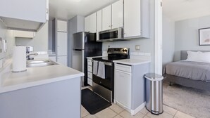 A compact kitchen with white cabinets, a stainless steel refrigerator, a microwave, and an oven. - Ocean View Oasis in Pacific Beach 2BR 2BA Balcony Pool  Monthly Stay (San Diego)