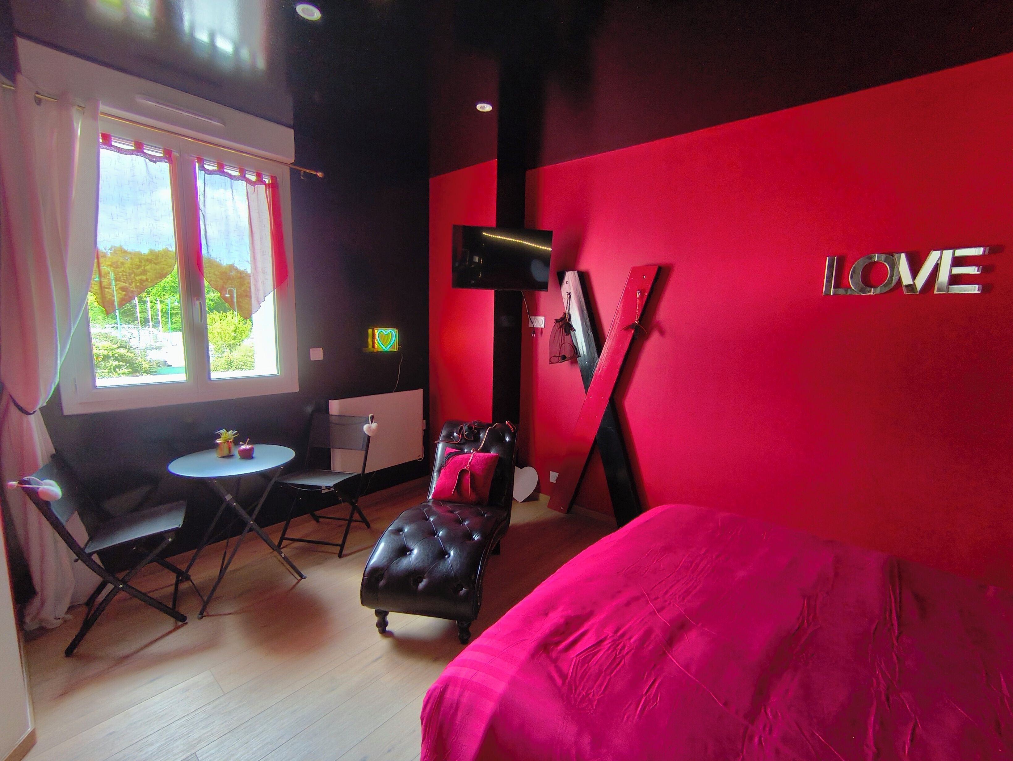 A room with a bed, a chair, a small table, and a window with curtains.