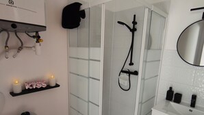Un baño moderno con ducha de vidrio, lavamanos blanco y un espejo.