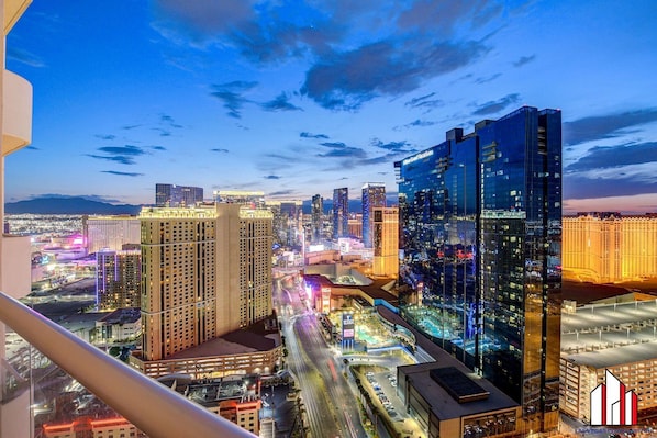 A high-rise hotel with multiple floors, a prominent glass facade, and a view of the cityscape at dusk.