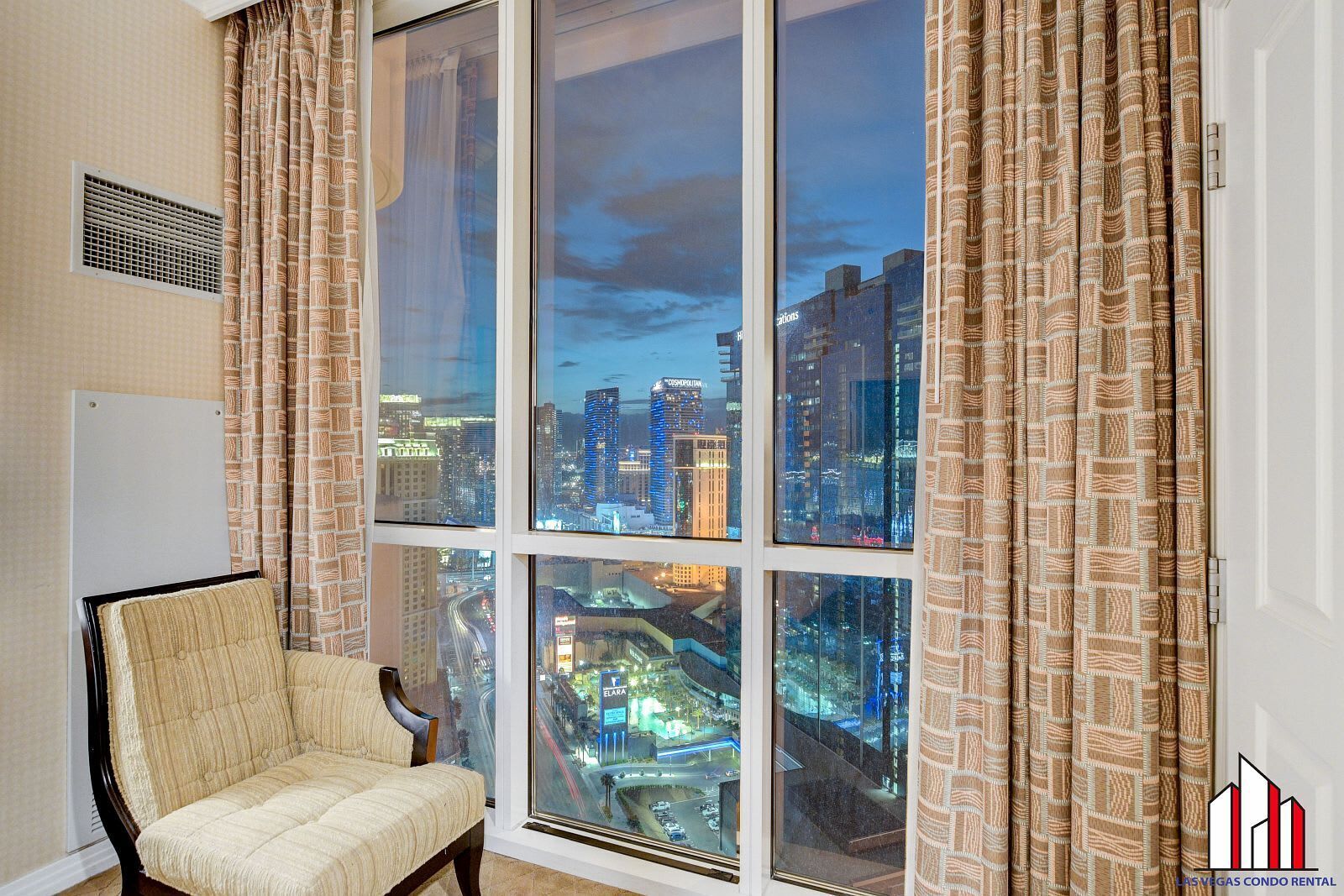 A room with a large window offering a cityscape view, a chair, and a whiteboard on the wall.