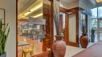 A modern interior with a reception area, large vases, and a dining space visible through the glass doors.