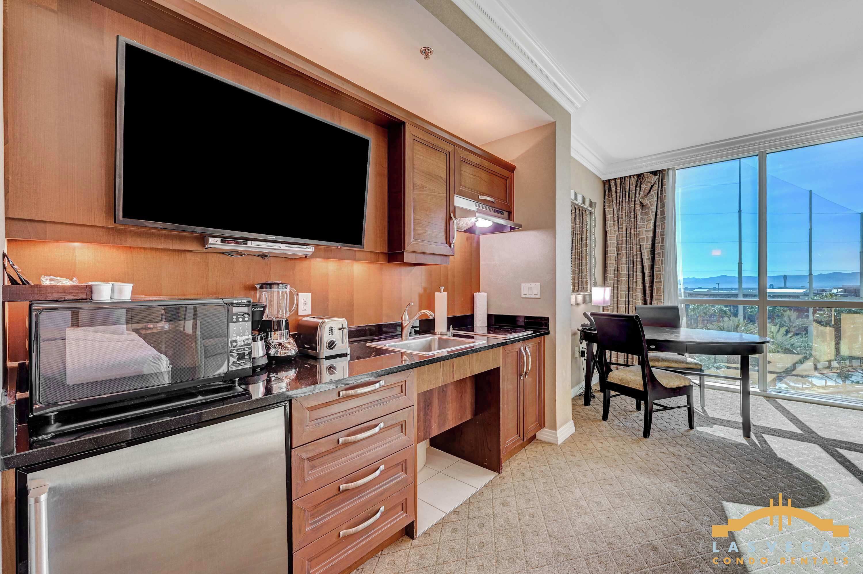 A modern kitchen with a flat-screen TV, a coffee maker, a toaster, and a blender.