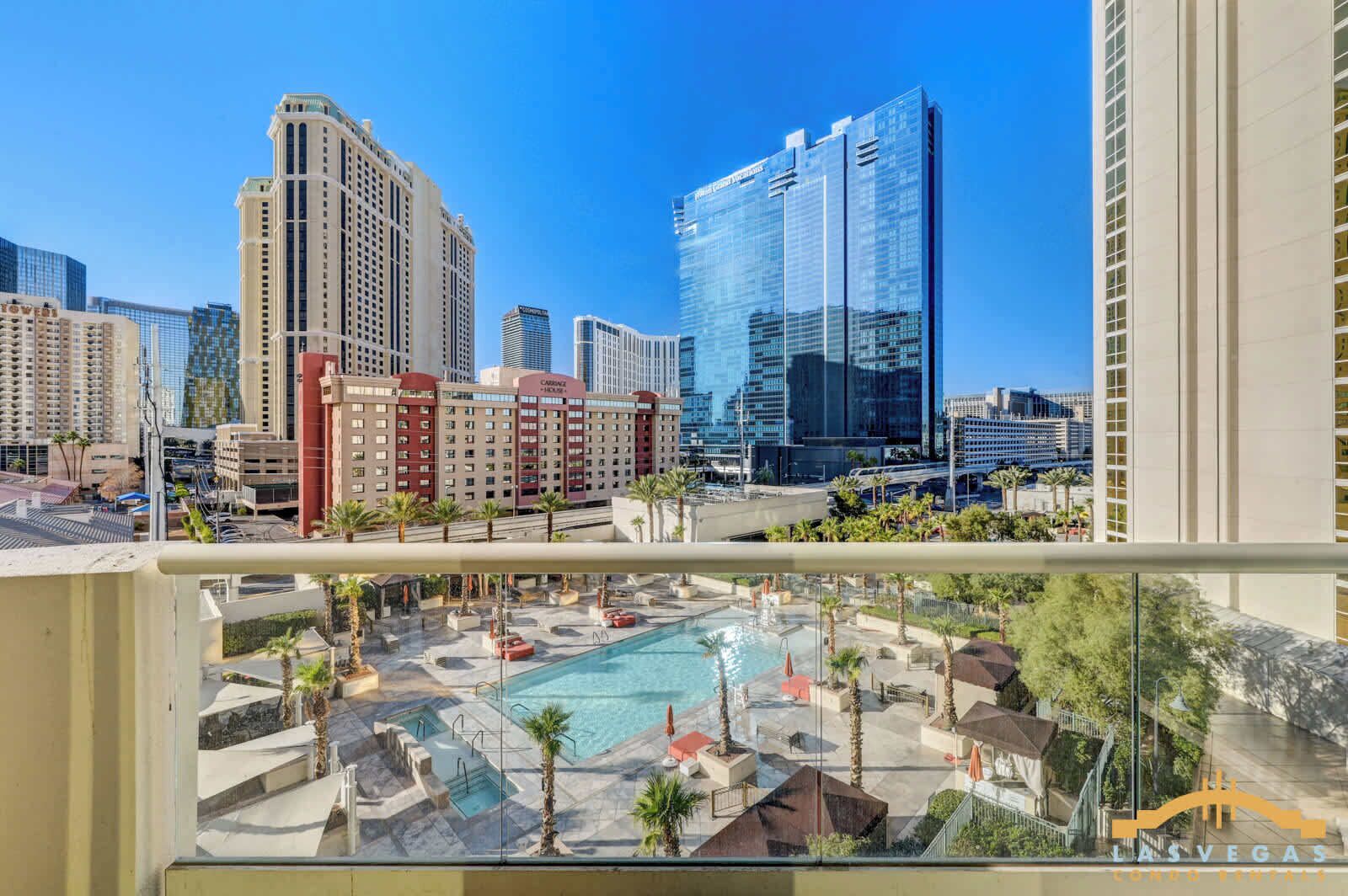 Un hotel con zona de piscina, varios edificios altos al fondo y un cielo azul despejado.