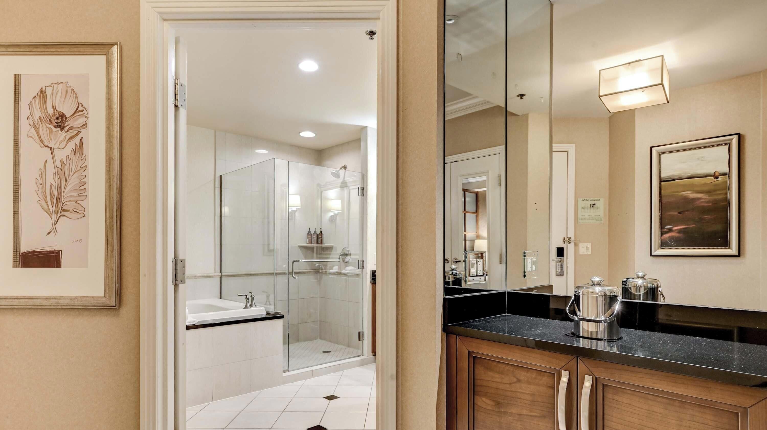 A modern bathroom with a glass shower enclosure, a large mirror, and a coffee maker on the counter.