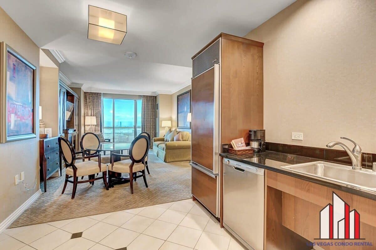 A modern kitchen with a refrigerator, sink, and dining area with chairs and a table.