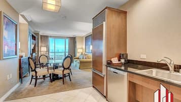 A modern kitchen with a refrigerator, sink, and dining area with chairs and a table.