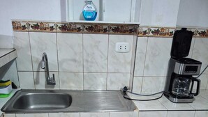 A kitchen with a sink, a coffee maker, and a bottle of hand soap on the countertop. - Apartment in Barrio de San Blas (Cusco)
