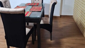 A dining area with a glass table, four upholstered chairs, a flat-screen TV mounted on the wall, and a wooden cabinet. - Apartment in Barrio de San Blas (Cusco)