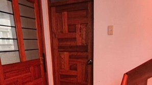 A wooden door with a geometric pattern, a black doormat, and a wooden staircase. - Apartment in Barrio de San Blas (Cusco)