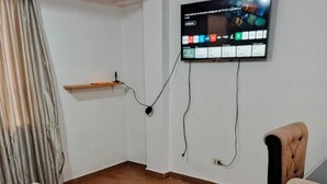 A room with a wooden floor, a television mounted on the wall, a small wooden table, and a chair. - Apartment in Barrio de San Blas (Cusco)