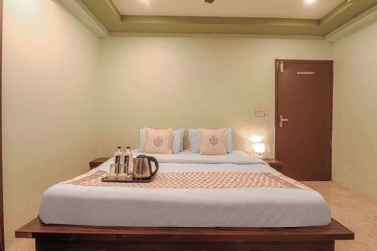 A hotel room with a bed, bedside table, and a door.