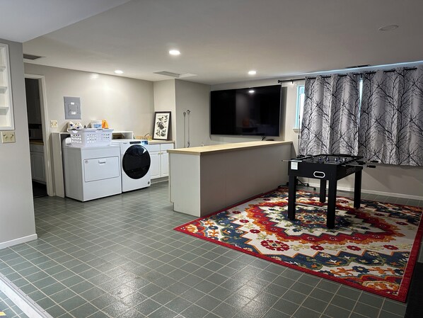 A compact living space with a washing machine, a foosball table, and a television.
