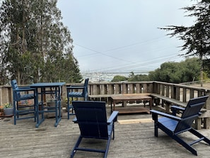 A wooden deck with outdoor furniture, overlooking a marina with boats.