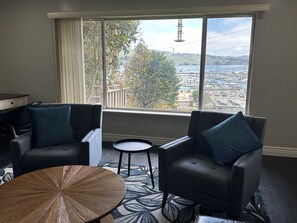 Una habitación con dos sillones de cuero, una mesita redonda y vistas a un puerto deportivo a través de amplias ventanas.