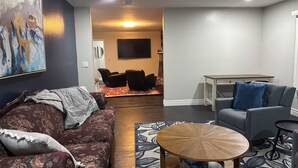 Una sala de estar con un sofá, una mesa de centro y un televisor al fondo.