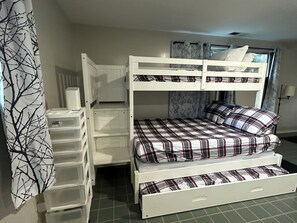 Una cama litera con una cama inferior, un escritorio pequeño y cajones para guardar objetos.