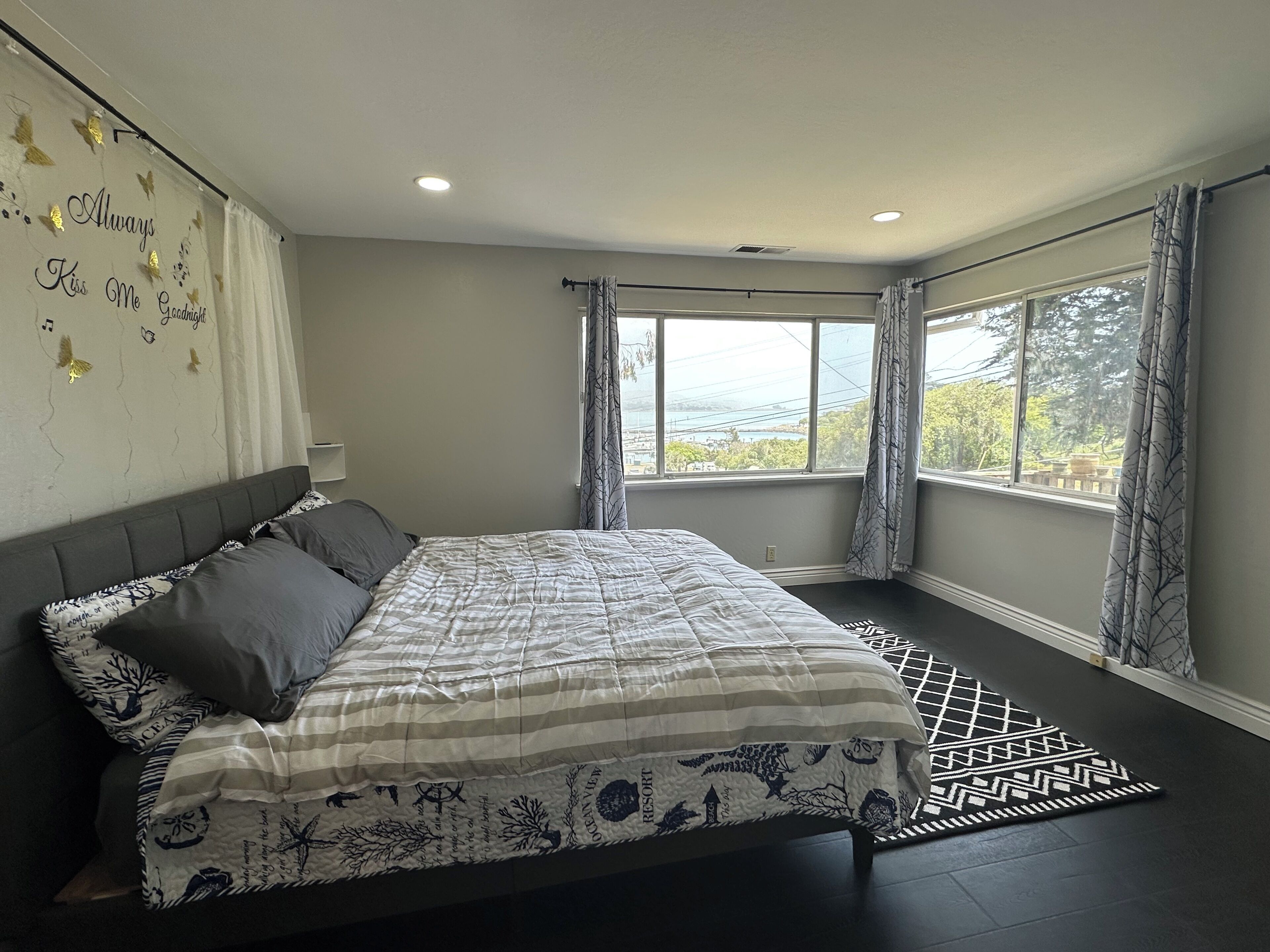 A bedroom with a bed, a window with curtains, and a view of the outdoors.
