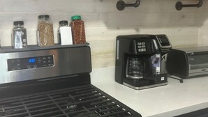 Una cocina equipada con cafetera, tostadora y microondas. Hay repisas superiores con condimentos y un adorno de pez.